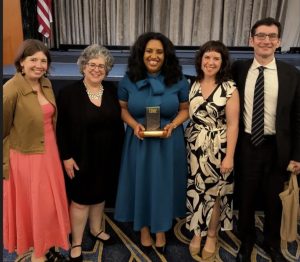 Kellye Garrett holding award in center, flanked by her publicist and agent on one side and editor and editorial director on the other